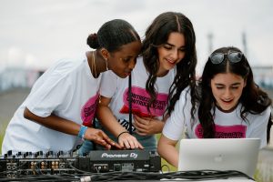 Foto di tre studentesse organizzatrici del festival che tengono un dj set