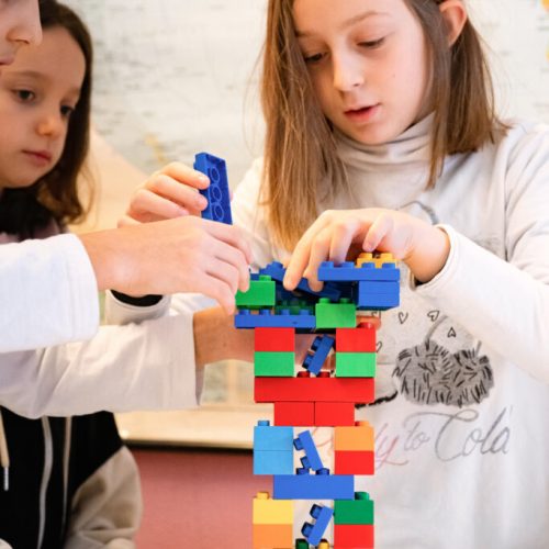 Foto di bambini che costruiscono una torre con dei blocchi Duplo